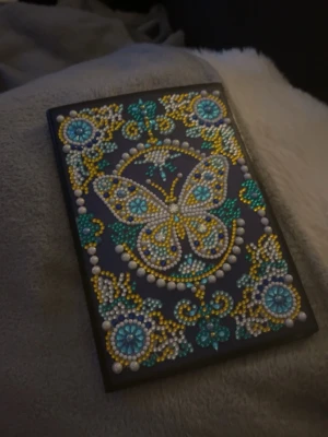 Skissbok med fjäril och pärlor - Gullig Tom ny skissbok med färgglad fjäril och blommönster i pärlor och strasstenar. Originalet är en enkel basic skissbok från rusta de är jag som har satt fast små pärlor och diamanter på, men har ej använt eller skrivit något inuti. Papperna är en storlek mindre än ”vanliga” A4 papper
