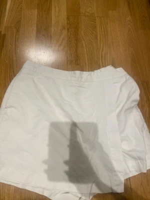 Vita skorts med omlott-look - Snygga vita skorts med omlott-design framtill och resår i midjan för extra komfort. Perfekta för en fräsch och stilren look. Tillverkade i ett lätt tyg som känns skönt mot huden. Från uniqlo 