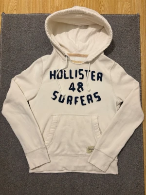Vintage Hollister Hoodie - Extremt sällsynt och unik Hollister Hoodie med tryck | Hoodien har en unik sliten & distressed design! | Mycket bra skick | Storlek S | Längd≈ 65 cm, Bredd 52 cm under armhål-armhåla| Modell 175cm, 68kg | Priset ej hugget i sten! 
