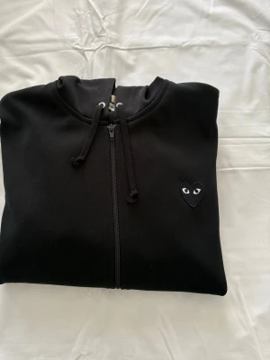 Svart hoodie från Comme des Garçons - Autentisk CDG hoodie. Röda färgen är ej på tröjan, utan det var kamerans effekt. Den är hel svart, all färg är fortfarande 100%. Ordinarie pris: 3500kr ✨8/10