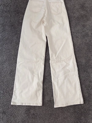 Vida vita jeans från Divided - Säljer ett par snygga vita jeans från Divided i storlek 36. De har raka, vida ben och två bakfickor. Perfekta till en avslappnad och trendig look. Materialet är kraftigt bomullstyg som ger en skön känsla och passar till många olika stilar.