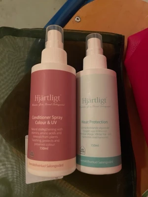 Hjärtligt duo heat protection & uv colour spray  - Två hårvårdsprodukter från Hjärtligt: en Conditioner Spray Colour & UV i rosa flaska och en Heat Protection i vit och turkos flaska. Båda är på 150ml och har sprayfunktion. Perfekta för att skydda och vårda håret med naturliga ingredienser.