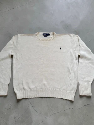 Vit stickad tröja från Polo Ralph Lauren - Klassisk vit stickad tröja från Polo Ralph Lauren med rund halsringning och den ikoniska lilla broderade loggan på bröstet. Tröjan har ribbade muddar vid ärmslut och nederkant. Perfekt för en clean och stilren look. Den i jättefint skick utan fläckar                                                                                      Nypris 2500kr