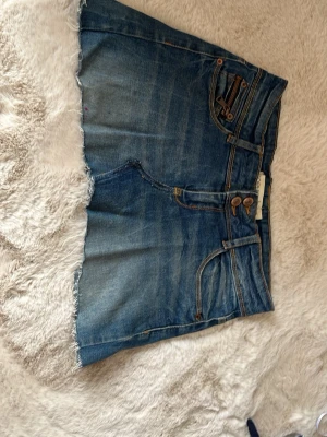 Blå jeanskjol med rå kant och dragkedjor - INTRESSEKOLL!! säljer en så vacker kjol - unik med dess design på fickorna (det går att öppna de, se bild 6!) och påminner om en vintage 2000s kjol😍lågmidjad också och vill se om nån är intresserad❤️