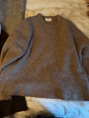 Beige stickad tröja Gina Tricot - Mysig beige stickad tröja från Gina Tricot i ullblandning. Tröjan har v-ringning, lång ärm och ribbade muddar vid hals, ärmslut och nederkant. Perfekt för kyliga dagar och enkel att styla till olika outfits.