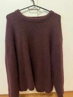 Mörklila stickad tröja Gina Tricot - Mysig mörklila stickad tröja från Gina Tricot i ullblandning. Tröjan har rund halsringning och långa ärmar, perfekt för kyliga dagar. Enkel och stilren design som är lätt att matcha med olika outfits.