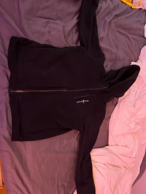 Svart hoodie från sailracing - Svart hoodie från sailracing med dragkedja framtill och broderad logga på bröstet. Tröjan har huva och är tillverkad i ett mjukt, fleeceliknande material. Perfekt för chill dagar eller när du vill ha något bekvämt och stilrent.PRISET KAN DISKUTERAS!