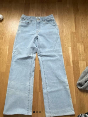 Ljusblåa raka jeans - Säljer ett par ljusblå jeans med rak passform och klassisk femficksdesign. Jeansen har hög midja och stängs med dragkedja och knapp. Perfekta för en avslappnad och trendig look.