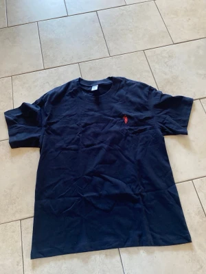 Marinblå t-shirt från Ralph Lauren - Snygg marinblå t-shirt med klassisk röd logga broderad på bröstet. T-shirten har rund halsringning och korta ärmar. Perfekt basplagg för en clean och stilren look.