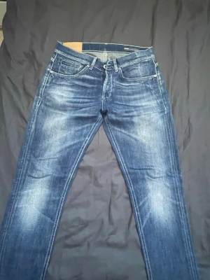 Blå jeans med slitningar från dondup - Snygga blå jeans med klassisk design och diskreta slitningar framtill och baktill. Jeansen har raka ben och tydliga kontrastsömmar. Perfekta för en avslappnad och trendig look.