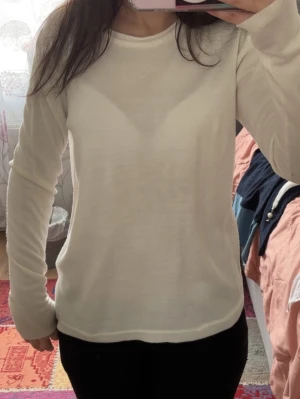Vit långärmad tröja  - En stilren vit långärmad tröja i mjukt och tunt material. Tröjan har rund halsringning och en enkel, klassisk design som passar till många olika outfits.
