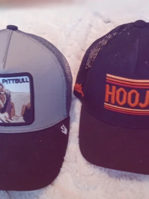 Fyra kepsar från Adidas, Nike m.fl. - Säljer fyra kepsar: en rosa Adidas med färgglatt logomönster, en vit Nike med svart logga, en grå/svart keps med Pittbull-märke och en svart keps med orange HOOJ-tryck. Alla har klassisk böjd skärm och justerbar baksida. Perfekta för dig som vill ha coola accessoarer. Säljs i paket pris för 340 kr. Den rosa kostar 75 kr. Den vita kostar 75 kr. Pitbull kostar 120 kr och hooja 100 kr om du vill köpa en keps bara. 