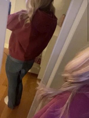 Vinröd hoodie med magficka - Säljer en vinröd hoodie med huva och stor magficka framtill. Hoodien har en avslappnad passform och ribbade muddar vid ärmslut och nederkant. Perfekt för en chill och bekväm stil. Materialet känns mjukt och skönt mot huden.