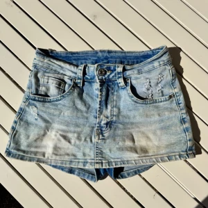XS Ljusblå kjol/shorts med slitningar - XS Ljusblå denimshorts /kjol med slitna detaljer. När man har dem på syns inte shortsen men det känns bra att det är shorts under den korta kjolen. 