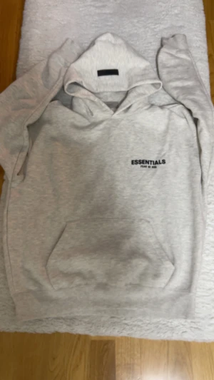 Essentials Hoodie - En ny grå essentials hoodie, mycket bra kvalité och är storlek Xs men är större så den passar S och även M inte använd så mycket kan skicka fler bilder!