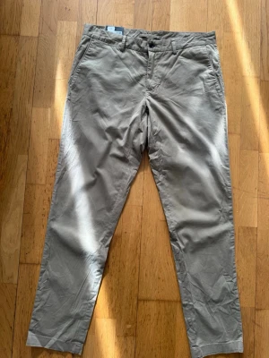 Chinos från J.Lindeberg  - Supersnygga helt nya oanvända chinos från J.Lindeberg. Modellen heter Chaze-Super Satin och har en klassisk rak passform med fickor fram och bak. Materialet är mjukt och har en satinliknande finish som ger en stilren look.