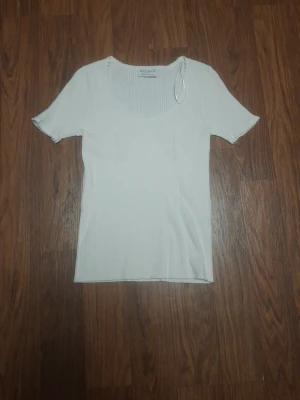 Vit ribbad topp från Lindex - Snygg vit ribbad topp från Lindex med korta ärmar och rundad halsringning. Toppens material är stretchigt och sitter figurnära, perfekt för en clean och enkel look.