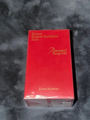Maison Francis Kurkdjian Baccarat Rouge 540 200ml - Maison Francis Kurkdjian Baccarat Rouge 540 Extrait de Parfum i en lyxig röd rektangulär kartong med guldfärgad text. Förpackningen har en elegant och exklusiv design med tydlig logotyp på toppen. Perfekt för dig som gillar exklusiva dofter.