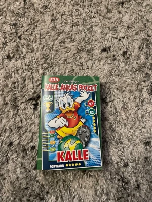 Kalle Ankas Pocket nr 538 - Kalle Ankas Pocket nummer 538 med fotbollstema. Omslaget är grönt med Kalle Anka i röd tröja och gula byxor, redo att sparka en fotboll. Baksidan visar Knatte som mittfältare. Perfekt för dig som gillar humor och äventyr i serieformat.