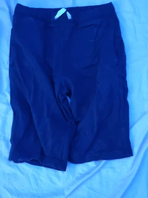 Mörkblåa shorts i bomull - Ett par enkla mörkblåa shorts i mjukt bomullsmaterial. Perfekta för varma dagar och har en klassisk, rak passform med resår i midjan. Stilrena och lätta att matcha med olika toppar.