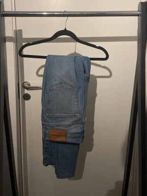 Ljusblå jeans från J.Lindeberg - Snygga ljusblå jeans från J.Lindeberg med klassisk femficksdesign och raka ben. Jeansen har en läderpatch med logga bak och är tillverkade i bomull. Perfekta för en avslappnad och trendig look.