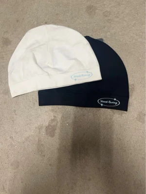 Två mössor från Secret Racing - Säljer två släta mössor från Secret Racing, en i beige och en i svart. Båda har logotypen tryckt på framsidan och är tillverkade i ett stretchigt material som sitter snyggt på huvudet. Perfekt för dig som gillar stilrena accessoarer med diskret branding.