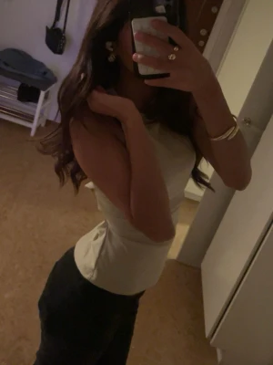 Knyttörja   - Säljer en ljusgul omlott topp med knyt i ryggen. Toppen är ärmlös och har en slim passform som framhäver midjan. Perfekt för dig som gillar stilrena och trendiga plagg. Materialet känns mjukt och lätt, troligen bomull eller syntet.