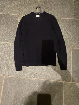 Mörkblå stickad tröja från These Glory Days - En enkel och stilren marinblå stickad tröja med rund hals och långa ärmar. Tröjan är gjord i mjuk bomull och har en klassisk passform som funkar till det mesta. 