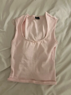 Ljusrosa ribbad linnetopp med rosett - Supersöt ljusrosa ribbad linnetopp från Gina Tricot med liten rosett framtill och djup rundringning. Perfekt till sommaren🤗!!Om du köper välj gärna att hämta vid upphämtningsställe då det blir enklare för mig att posta på det viset!!