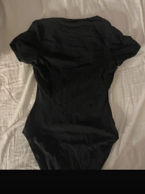 Svart kortärmad body från skims - Säljer en enkel och stilren svart body med korta ärmar. orginal pris var 800kr❤️ Bodyn har en klassisk rund halsringning och är tillverkad i ett mjukt, stretchigt material som sitter snyggt mot kroppen. Perfekt att matcha med jeans eller kjol för en clean look.