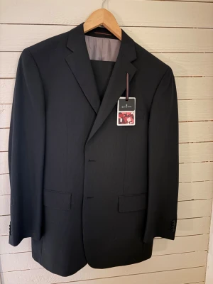 Oanvänd kritstrecksrandig kostym  - Helt ny kritstrecksrandig kostym från Batistini/Dressman. Byxor och kavaj.  Prislappen sitter kvar. Storlek 52