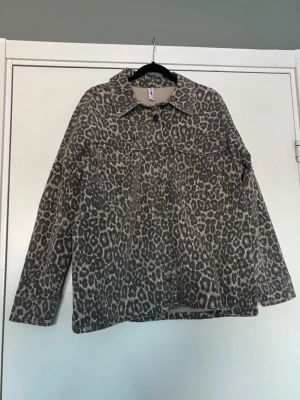 Leopardmönstrad jeansjacka - Cool jeansjacka med leopardmönster i bruna och svarta toner. Klassisk krage, knäppning framtill och två bröstfickor. 