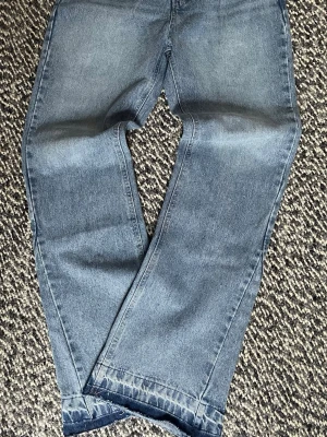 Blå zara bootcut jeans med rå kant - Säljer ett par blå bootcut jeans med rå kant längst ner. Jeansen har klassiska fickor bak och är gjorda i denim. Perfekt för dig som gillar en avslappnad och trendig look.
