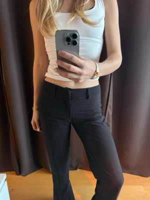 Svarta kostymbyxor med raka ben - Säljer ett par svarta kostymbyxor med raka ben och klassisk passform. Byxorna har hällor för skärp och stängs med dragkedja och hake. Oanvända.