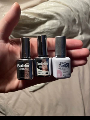 Gel Builder och Gel iQ nagellack - Tre flaskor nagellack från Depend: två Gel Builder UV/LED-lack i svart och soft white samt ett Gel iQ UV/LED-lack i färgen Pink Strawberry. Alla flaskor har silvriga lock och är perfekta för att skapa snygga gelnaglar hemma.