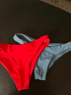 Två bikinitrosor i rött och ljusblått - Säljer två bikinitrosor i klassisk modell, en i starkt röd och en i ljusblå färg. Båda är enkla och stilrena utan mönster eller extra detaljer, perfekta för stranden eller poolen.