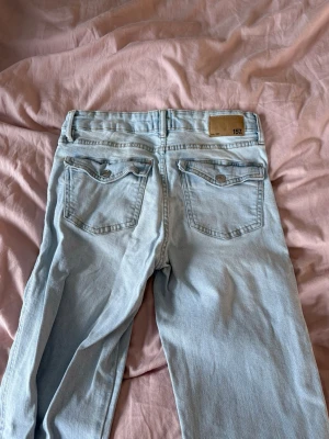 Ljusblå 90’s bootcut jeans från 157 - Säljer ett par blå bootcut jeans från lager 157. Snygga fickor bak. Hål i knäna. Endast använda två gånger. Storlek M. Jag är 172 lång och dom är långa på mig💕
