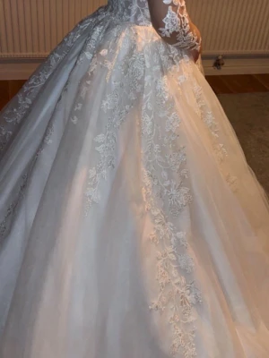 Bröllopsklänning  - Vacker brudklänning med långa ärmar och detaljerad spets. Klänningen har en lång släp och en matchande tiara. Nypris 18500kr från bröllopsspecialisten , har även kvitto om man önskar de, den är inte kemtvättad o såklart använd en kväll(underkjol och tiara ingår)