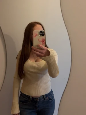 Beige  långärmad tröja från Gina tricot - Säljer en beige ribbad tröja med lång ärm och djup rundad halsringning. Tröjan är figurnära och har en mjuk, stretchig känsla som passar perfekt till jeans. 