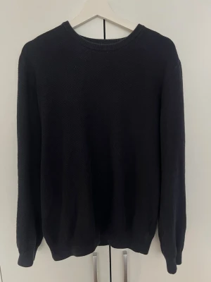 Mörkblå stickad tröja från These glory days - En enkel mörkblå stickad tröja med rund halsringning och långa ärmar. Tröjan har ribbade muddar vid ärmslut och nederkant. Perfekt basplagg för lager på lager och passar till det mesta. 