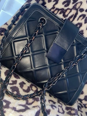 Snygg kedja väska - Säljer en snygg kedje väska med extra ”stängning” med en knapp och tillräckligt stor för att ha allt du behöver! Färgen har rostat lite dock. 