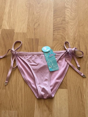 Bikini underdel - Lila bikini underdel med knytdetalj. Har aldrig använts innan och är helt ny med prislapp. 
