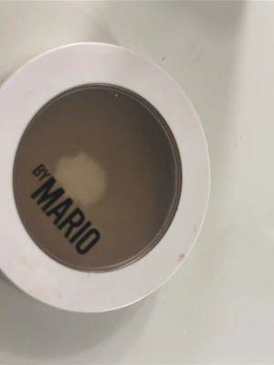 By Mario SoftSculpt Bronzer Medium - Bronzer från By Mario i nyansen Medium. Kommer i en rund, vit plastförpackning med genomskinligt lock. Produkten har en varm, brun ton som ger huden innerlig lyster och definition. Perfekt för att skapa en solkysst look och framhäva ansiktskonturer.