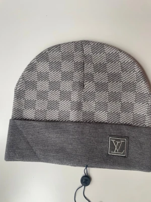 Grå mössa med rutmönster - En väldigt fin grå mössa som aldrig har blivit använd!! Priset kan diskuteras!! Påse med följer