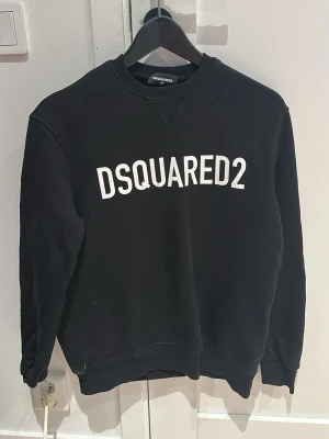 Svart sweatshirt från Dsquared2 - Svart sweatshirt från Dsquared2 med vit logotyp tryckt över bröstet. Klassisk rund halsringning och ribbade muddar vid ärmslut och nederkant. Perfekt för en avslappnad och trendig look. Strlk 16 years men skulle passa mellan xs-s beror på vikt köpt på farfetch