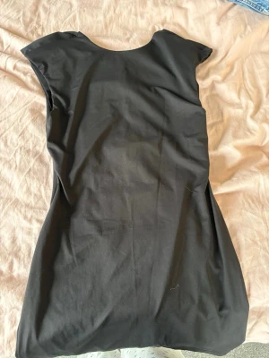 Svart kortärmad klänning - Säljer en svart figursyd klänning. Öppen i ryggen. Aldrig använd endast testad. Storlek M.💕