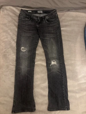 Svarta bootcut jeans LTB - Snygga svarta bootcut jeans med slitningar på båda knäna och diskreta ljusa tvättade detaljer, låg midja. W27 L30