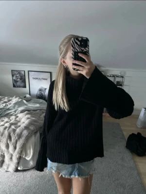 Svart ribbstickad tröja med polokrage - Säljer en svart ribbstickad tröja med polokrage och långa ärmar. Tröjan har en avslappnad passform och är perfekt för lager på lager. Materialet ser mjukt och bekvämt ut, och modellen är enkel men stilren.