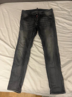 Grå Dsquared2 jeans, storlek 46 - Snygga grå jeans från Dsquared2 i storlek 46. Jeansen har en tvättad look med ljusare partier, klassiska fem fickor och svart Dsquared2-läderpatch bak. Materialet är bomull med lite stretch för skön passform. 