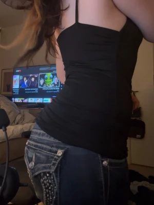 Svart figurnära linnetopp - Snygg svart linnetopp med smala axelband och figurnära passform. Toppen har en enkel, stilren design och är perfekt att matcha med jeans eller kjol. Materialet känns mjukt och stretchigt, vilket gör den bekväm att bära hela dagen.